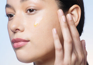 Woman applying Reset serum on the face smiling.
