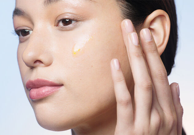 Woman applying Reset serum on the face smiling.